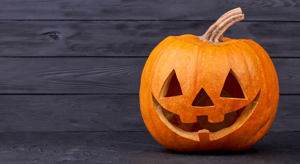 Carved Halloween pumkin on a dark stained floor.